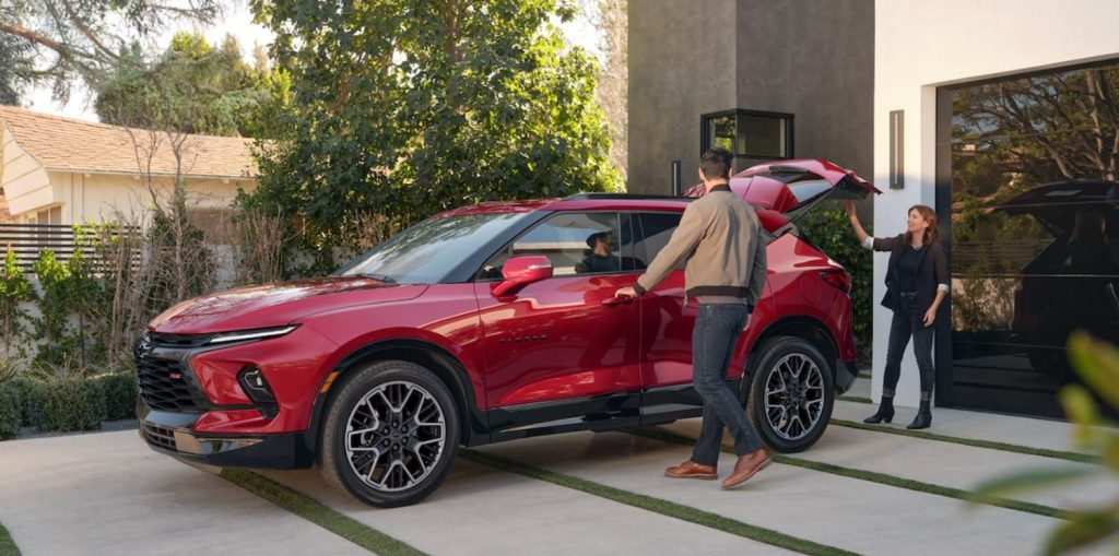 A red 2022 Chevrolet Blazer parked in a driveway with the owners packing and getting into the car.