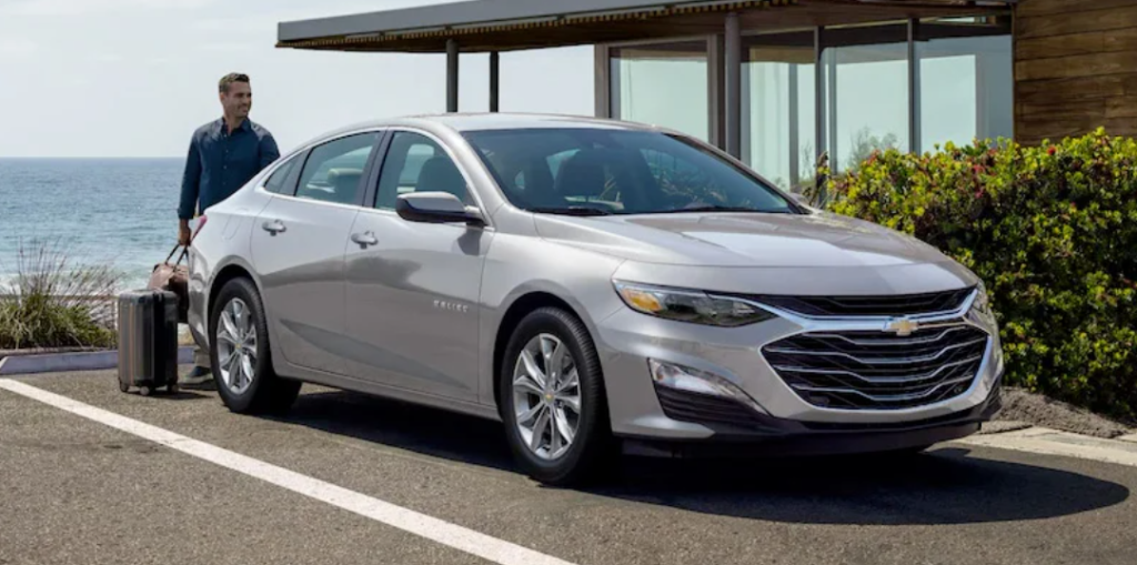 A man getting into his white 2022 Chevrolet Malibu.