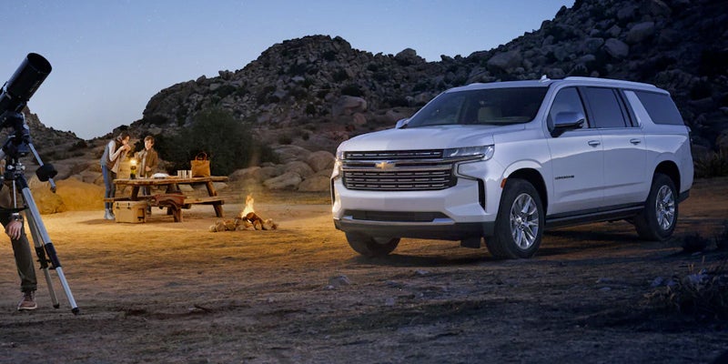 A white 2023 Chevy Suburban parked at a camp site.