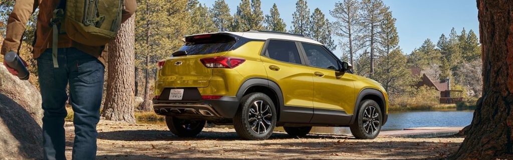 Yellow Chevrolet Trax SUV parked near a forest lake with outdoor scenery
